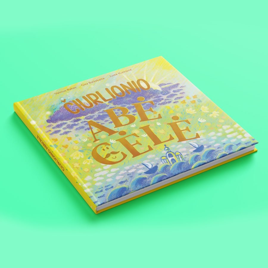 A colorful hardcover book titled “Čiurlionio abėcėlė” lying on a bright mint-green background, featuring a dreamy illustrated cover with flowers, clouds, and birds.