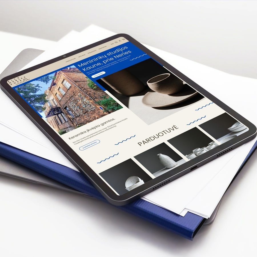 Tablet displaying an art studio website with ceramic works, studio information, and an online shop layout on a clean white desk.