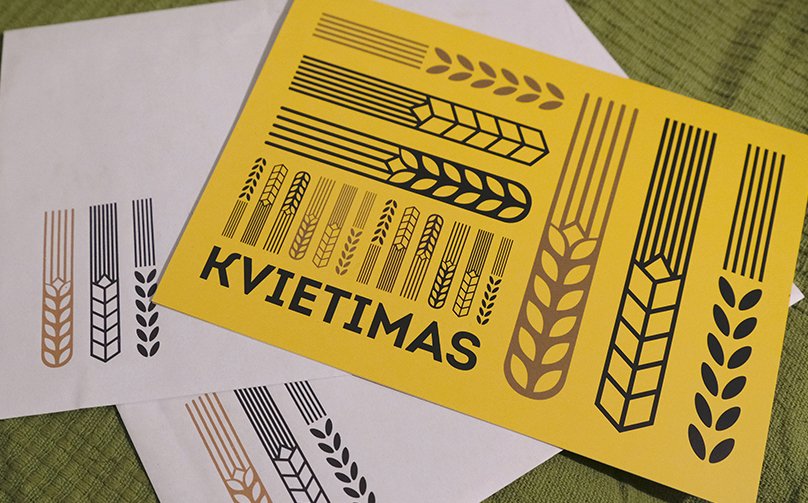 A bright yellow invitation card with bold black and gold grain illustrations lies on matching printed envelopes; the large text reads “Invitation.”