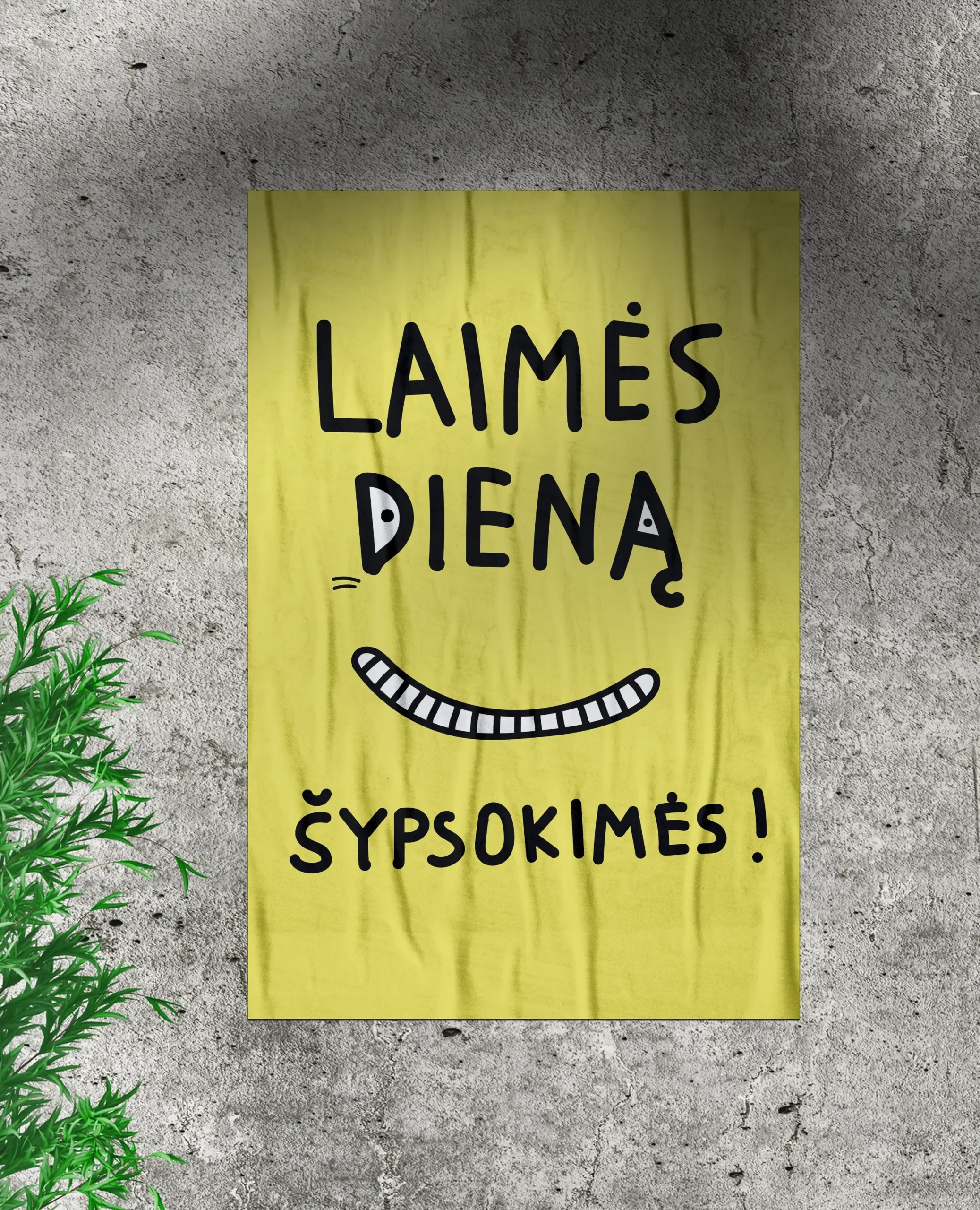 A bright yellow poster on a grey concrete wall features playful black lettering and a wide illustrated smile. The text reads: “LAIMĖS DIENA. ŠYPSOKIMĖS!” (“Day of Happiness. Let’s smile!”).