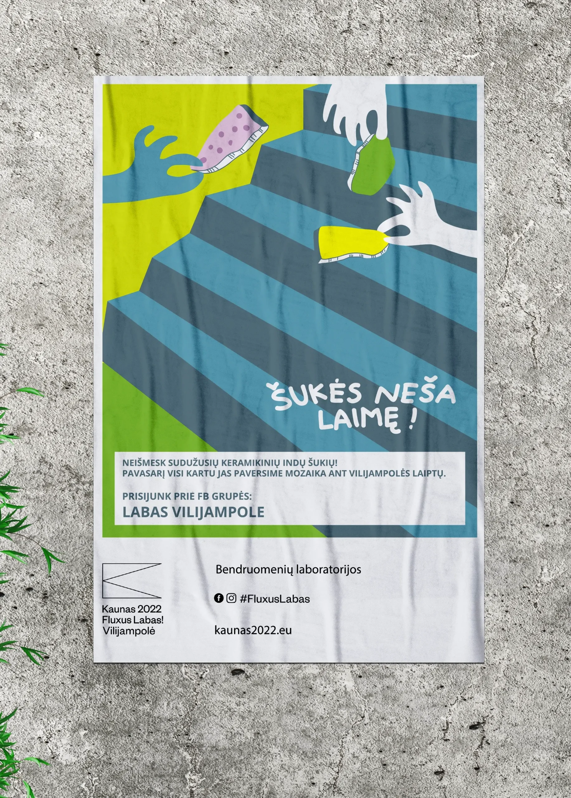 A colourful poster on a concrete wall shows several illustrated hands carrying broken pieces of ceramic dishes up a striped staircase. Large text reads “Šukės neša laimę!” (“Broken pieces bring good luck!”). The poster asks residents not to throw away broken ceramic dishes, but to save them for a community mosaic on the Vilijampolė steps in spring. It also invites people to join the Facebook group “Labas Vilijampole” and includes “Kaunas 2022 Fluxus Labas! Vilijampolė,” “Bendruomenių laboratorijos,” “#FluxusLabas,” and “kaunas2022.eu.”