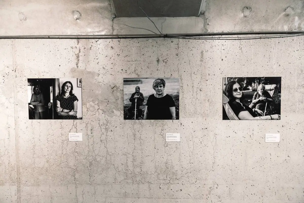 Three black-and-white photographic portraits of women and their family members displayed on a concrete gallery wall.
