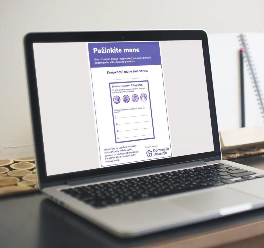 A laptop displaying the cover of an interactive PDF titled “Get to Know Me,” designed for people living with dementia. The form includes fillable fields for a preferred name, personal photograph and favourite things, with purple icons and the Dementia Lithuania logo.